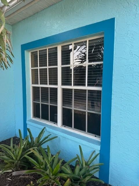 Turquoise stucco home with a new grid window and fresh paint around the opening