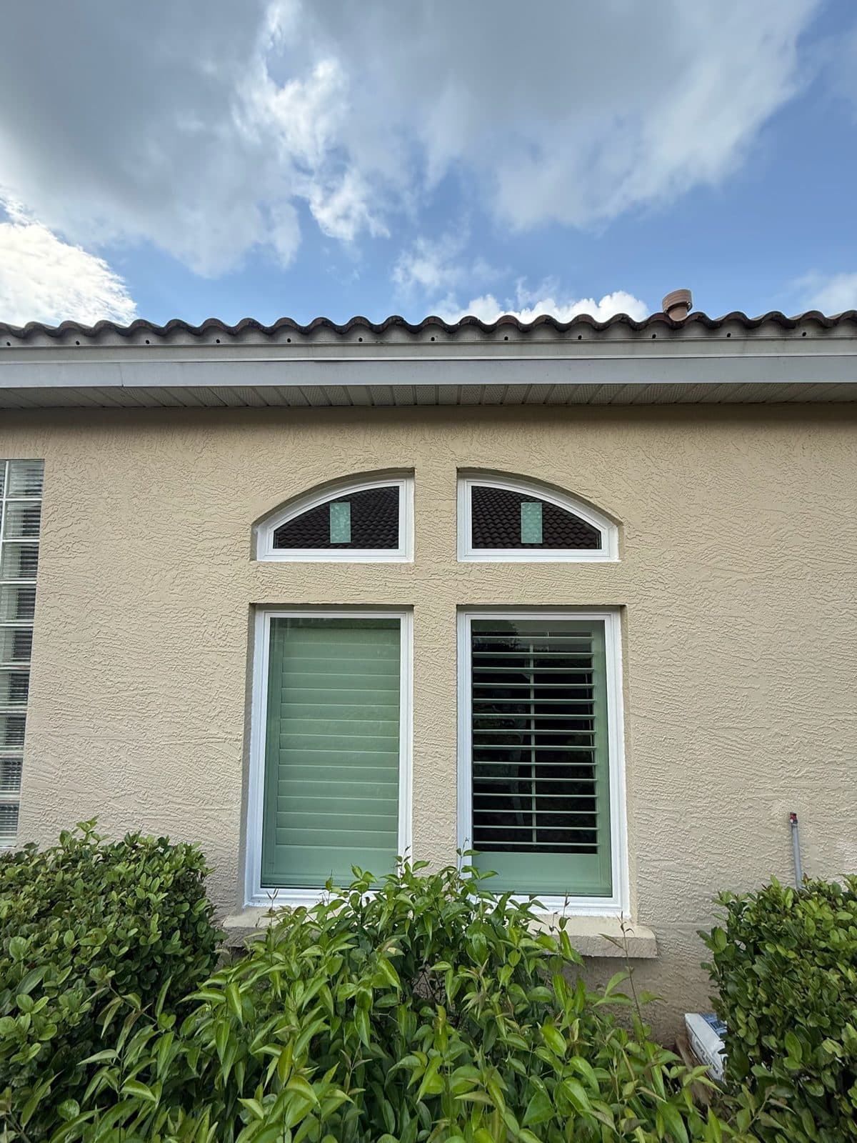 Two arched eyebrow transom windows over two rectangular windows in tan stucco under a tile roof, Lakewood Ranch