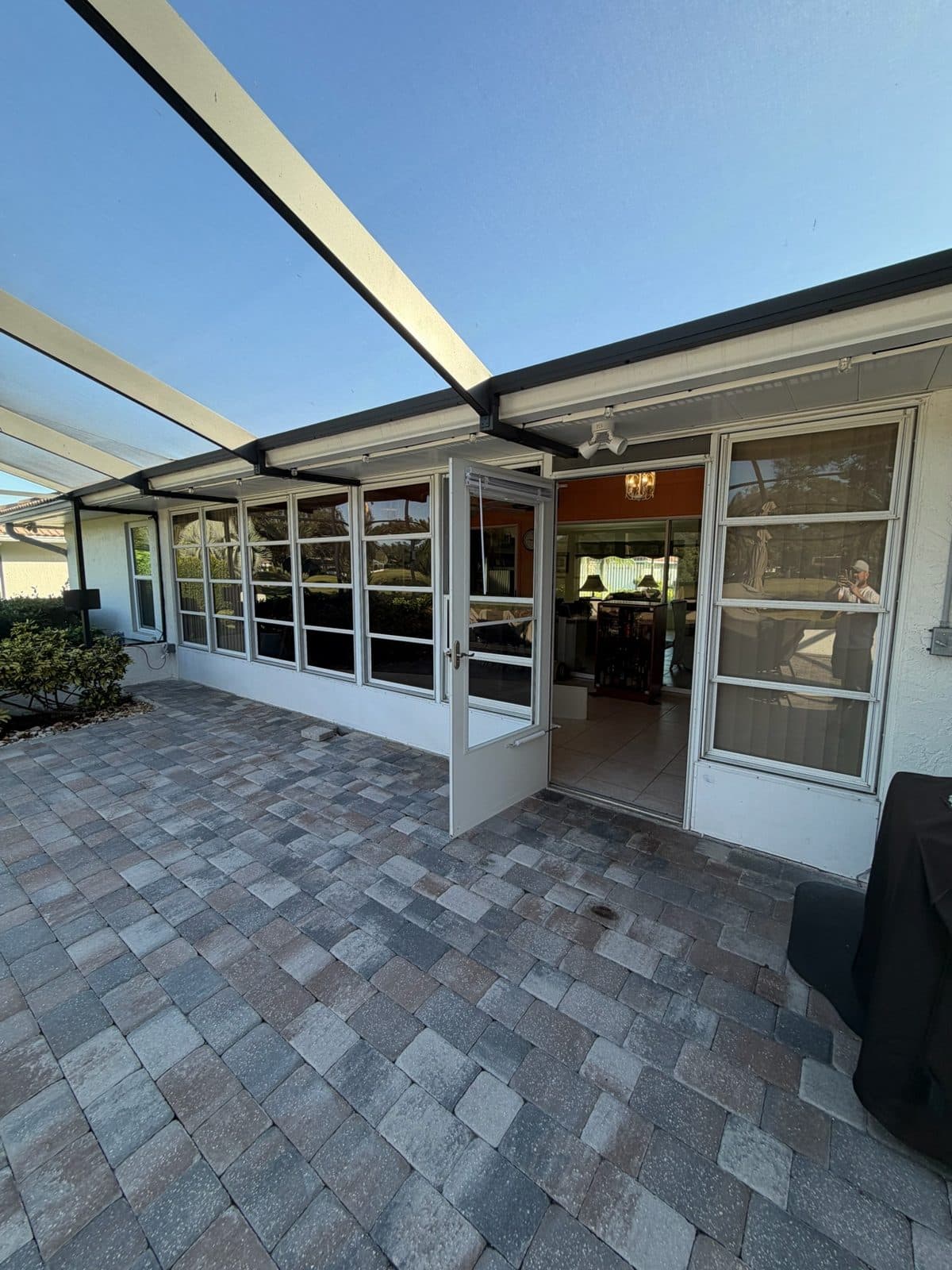 Old aluminum-framed lanai wall with glass panels before replacement, Manatee County