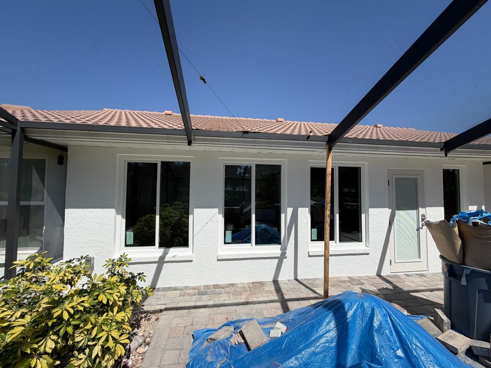 After: new white stucco block wall on a Manatee County lanai with three two-lite storm-rated windows, a full-lite door and a tall narrow window under the screen enclosure