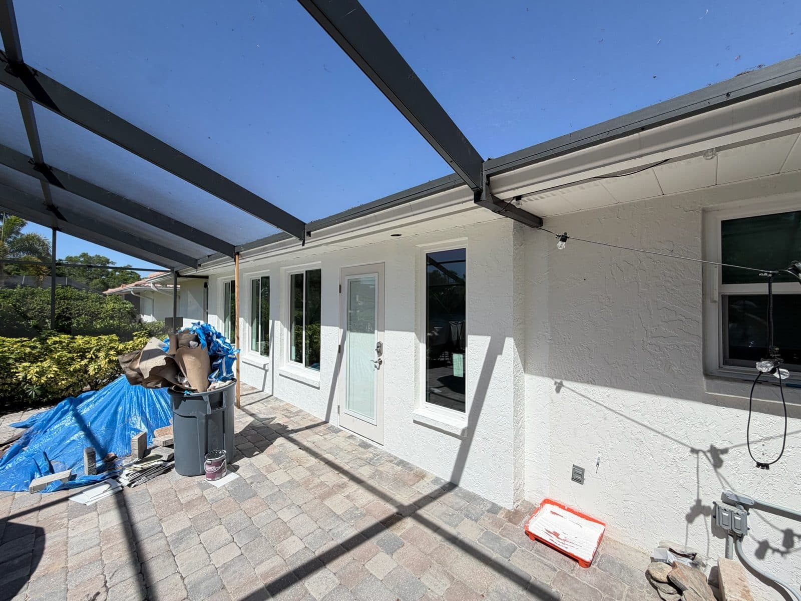 Rebuilt stucco block lanai wall with new windows under a bronze pool cage frame, Manatee County