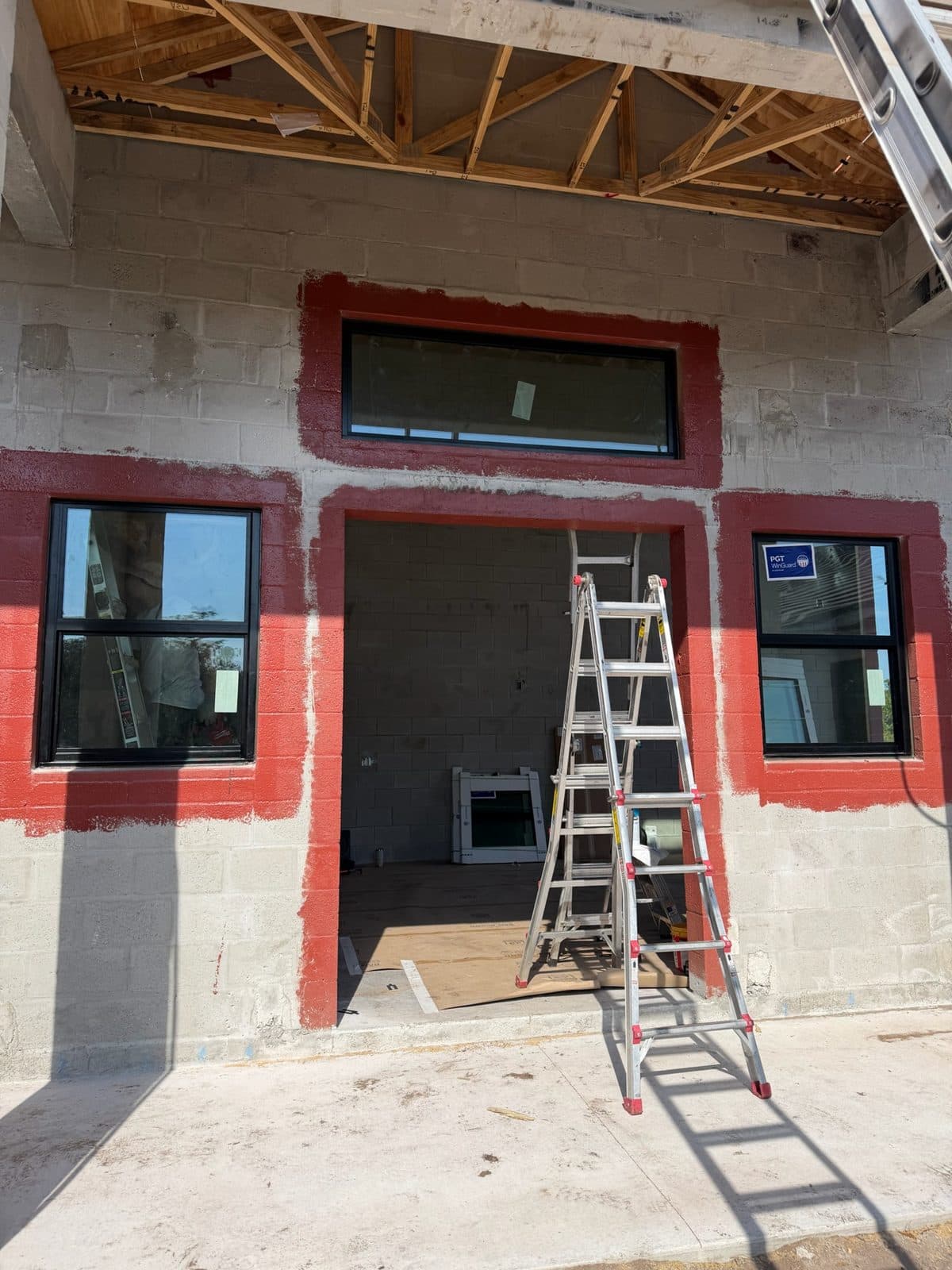 Rough openings wrapped in red liquid-applied flashing with black impact windows installed, Parrish FL