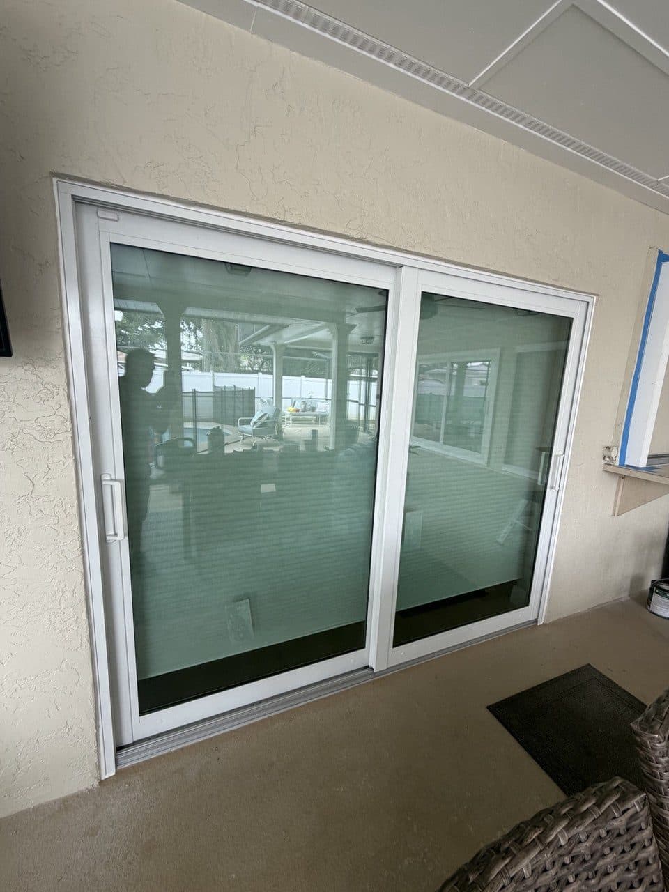 New sliding glass door with the pool lanai reflected in the glass