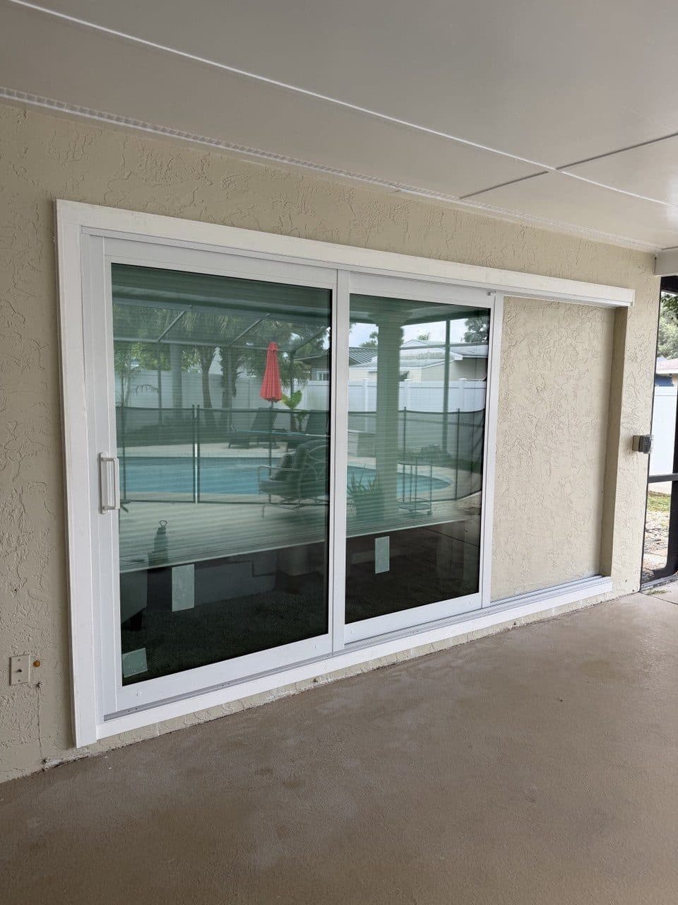 Sliding glass door on a pool lanai with the pool visible through the glass
