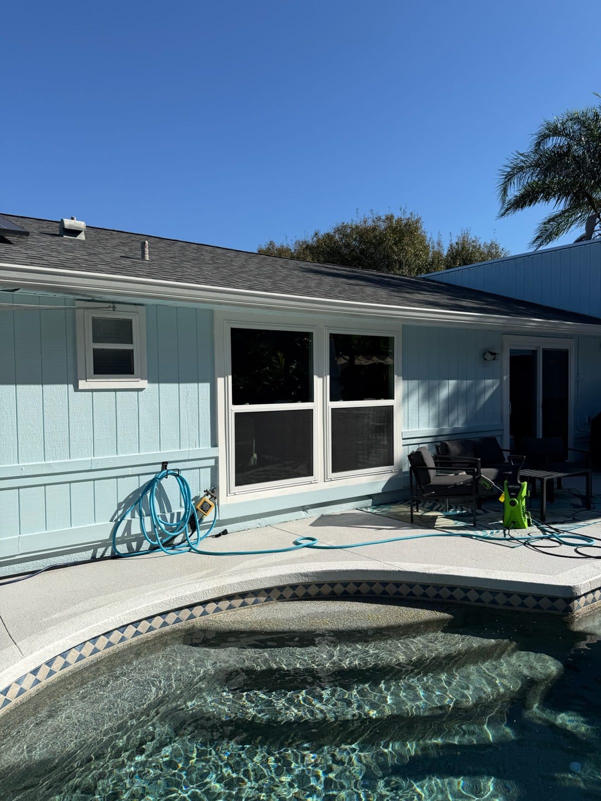 Pool and back of a light blue Sarasota home with new windows