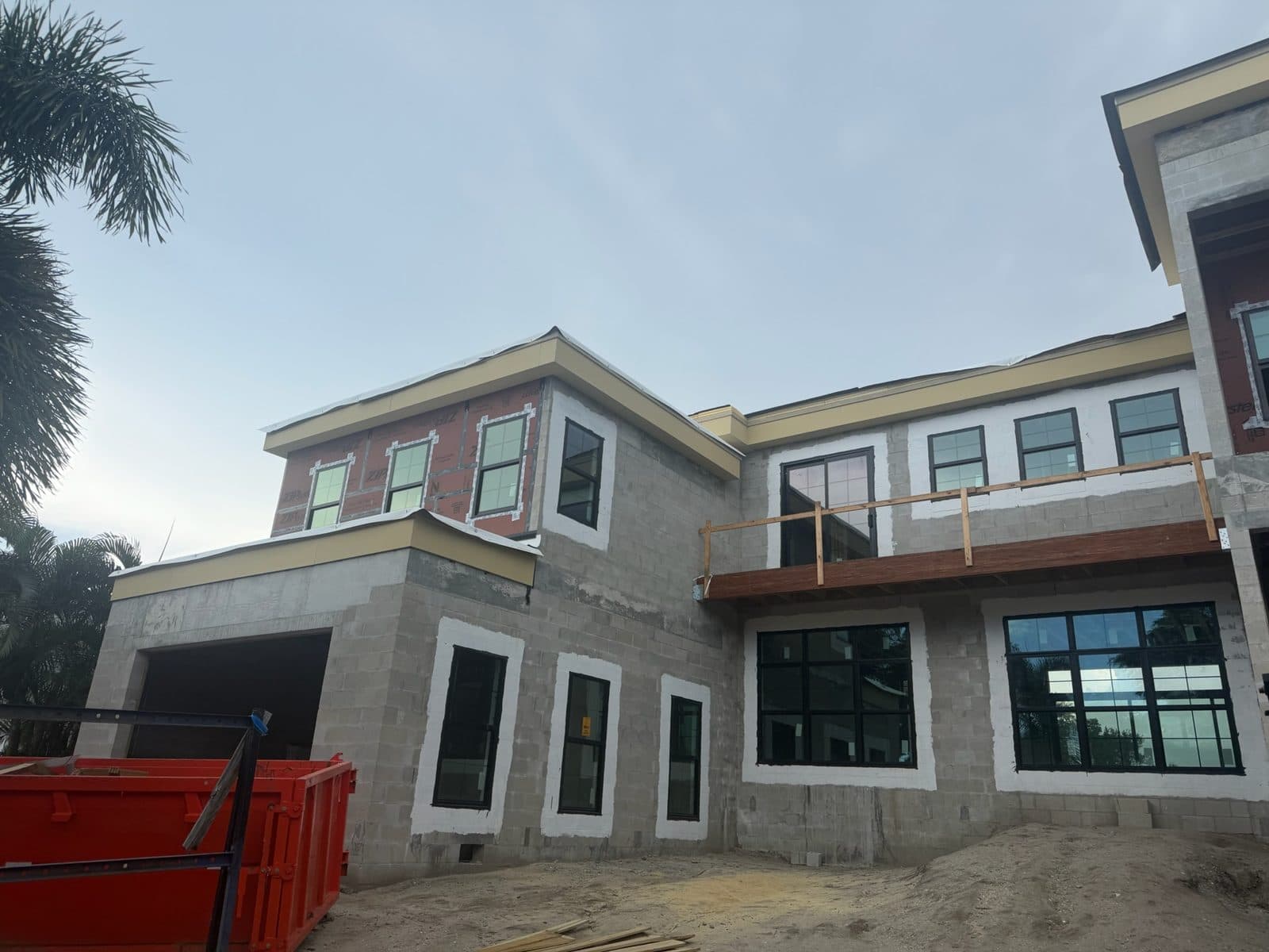 Two-story block new construction home on Siesta Key with black-framed windows set in white-sealed openings and a balcony with temporary rail