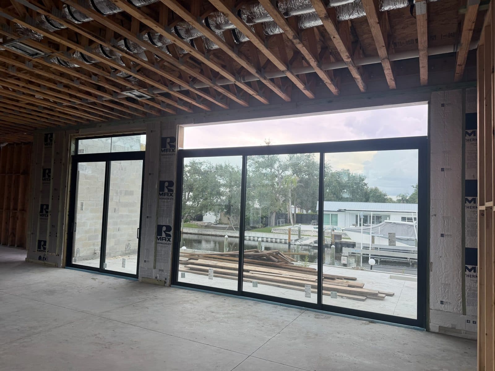 Black-frame multi-panel impact sliding door wall facing a canal in a new Siesta Key home