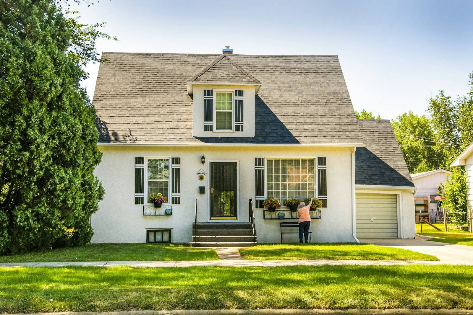 White house with a green lawn and mature trees