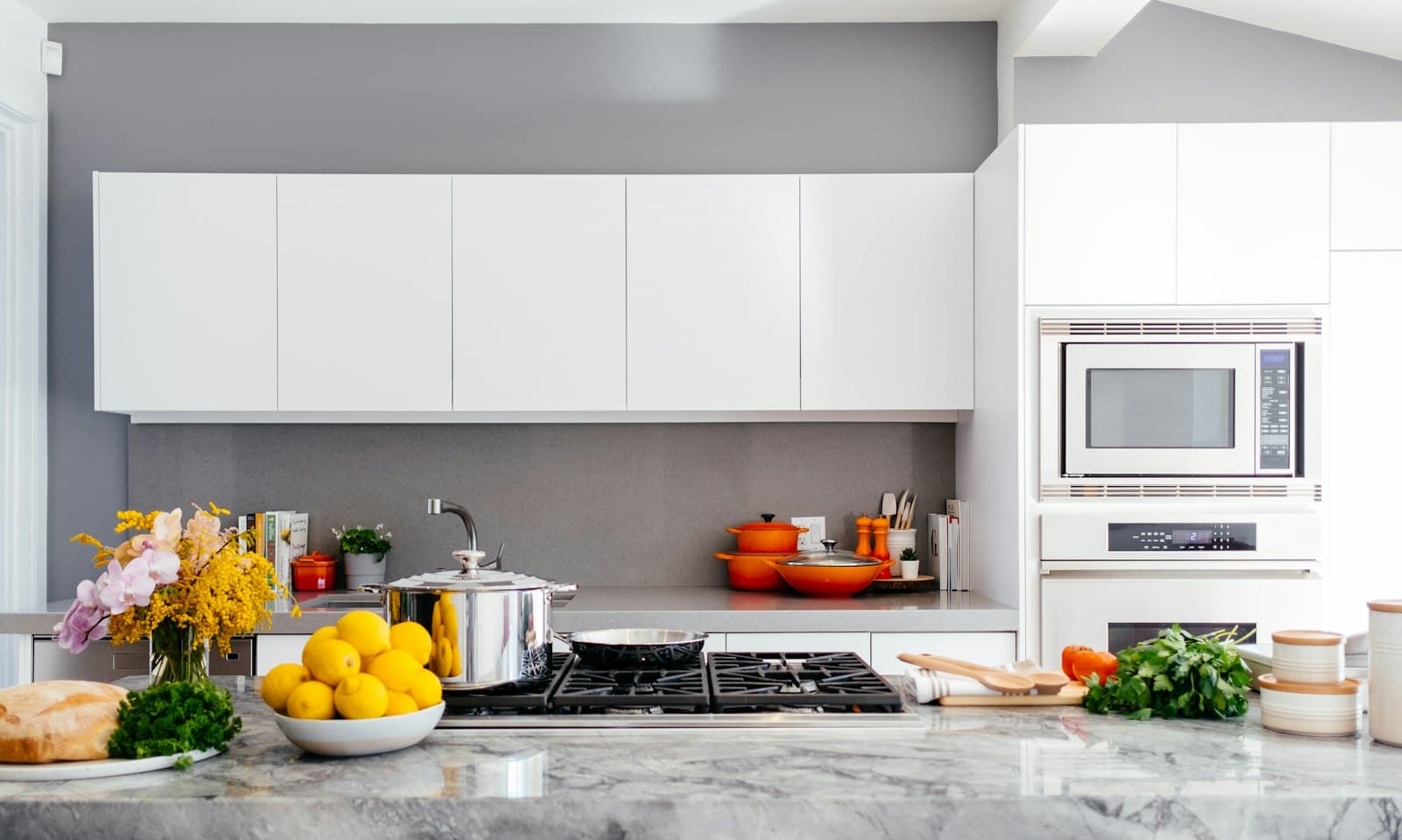 Bright white kitchen with a marble-topped island and pendant lights