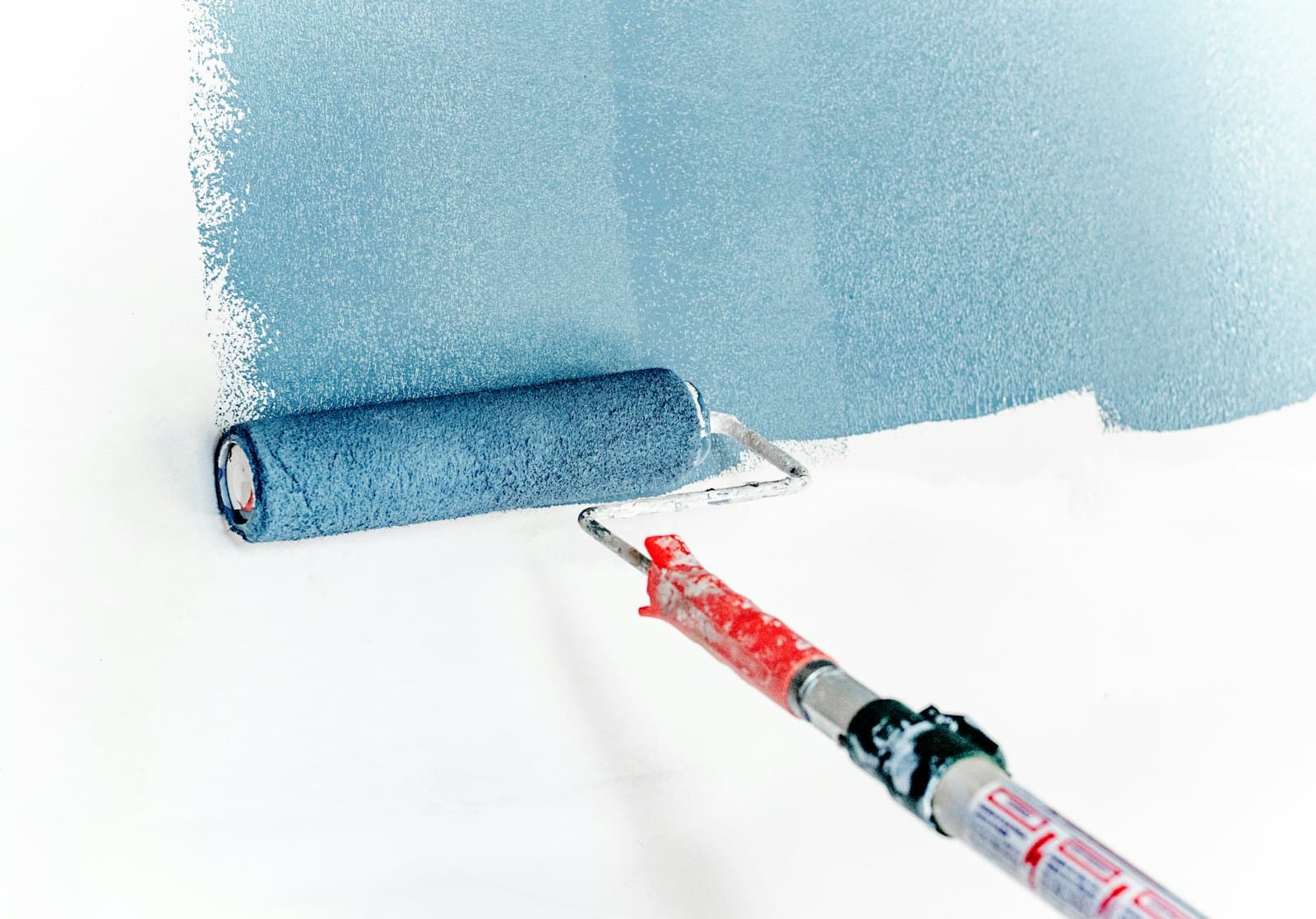 Paint roller applying color to a white interior wall