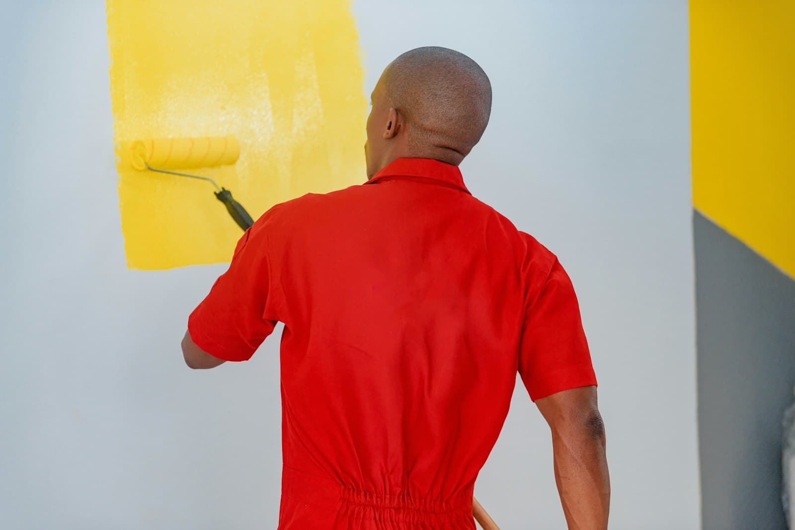 Painter rolling yellow paint onto a wall