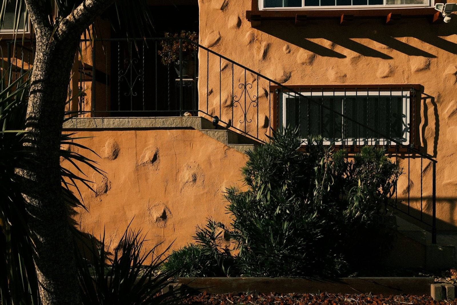 Exterior of a stucco home with front steps and plantings