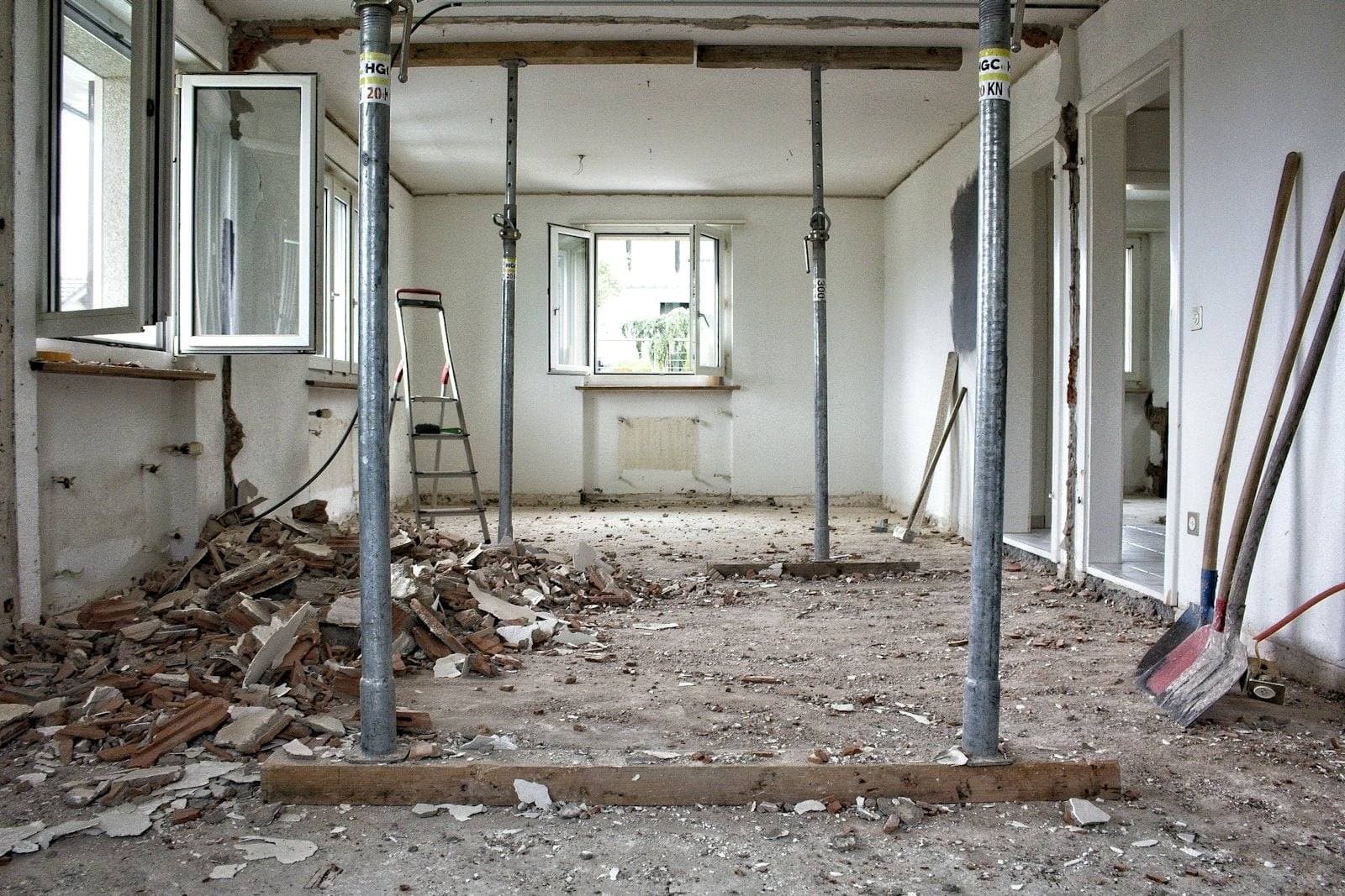 Room gutted during renovation with temporary shoring posts and tools on the floor